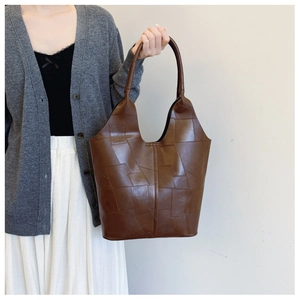 Detail of deep brown leather tote bag showing irregular geometric patchwork and stitching