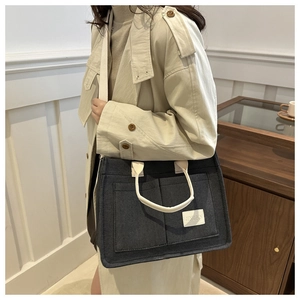Détail du sac cabas en feutre gris foncé avec poignées blanches et poches frontales