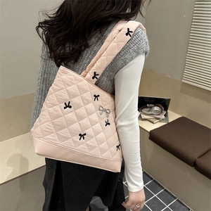 Pink quilted tote bag with black bow embroidery and silver charm shown on model