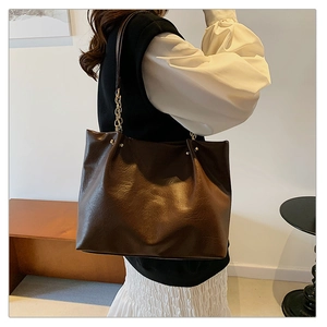 Détail du grand sac cabas marron foncé avec texture en cuir brillant et chaîne