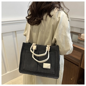 Détail du sac cabas en toile noire avec sangles crème et doubles poches avant