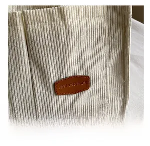 Detail of off-white corduroy bag showing leather patch with FASHION & BAGS logo