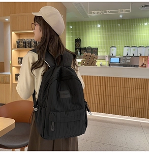 Detailed view of the black pleated backpack showing its unique texture in a cafe setting