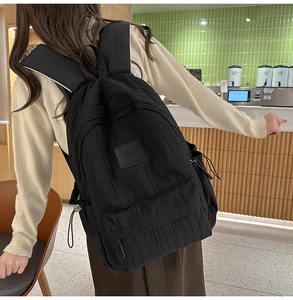 Side view of black vertical stripe backpack with logo patch on green tiled background