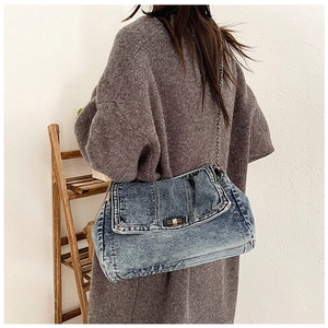 Detail of vintage denim shoulder bag with metal chain strap and turn-lock closure