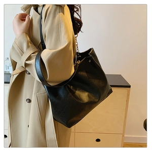 Détail du grand sac cabas en cuir souple noir avec chaîne métallique élégante et bandoulière large