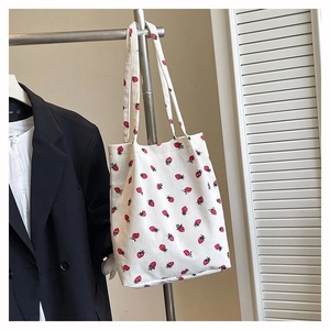 Dettaglio della borsa tote in velluto bianco con stampa di fragole rosse su una gruccia