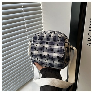 Detail of blue plaid canvas crossbody bag with heart print and adjustable strap