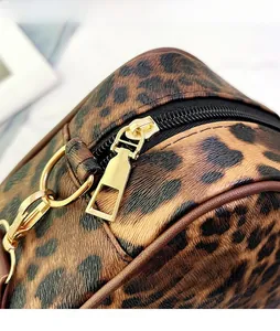 Detail of leopard print travel bag featuring golden metal zipper and textured PU leather