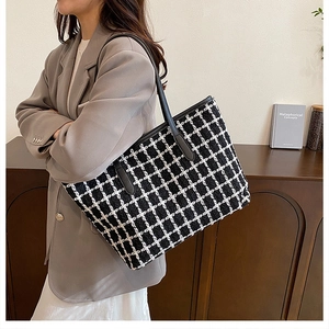 Dettaglio della grande borsa tote a scacchi con texture intrecciata e manico in pelle nera