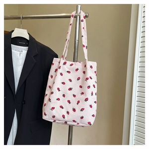 Dettaglio della borsa tote in velluto a coste rosa con stampa di fragole rosse
