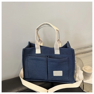 Détail du sac cabas en toile marine avec poignées tissées blanches et poches de rangement