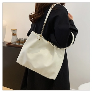 Détail du cabas blanc en cuir PU avec élégante chaîne dorée sur un manteau noir