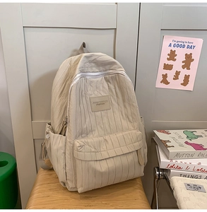 Close-up of minimalist beige backpack with crinkle texture fabric and front zipper pocket
