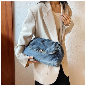 Detail of vintage denim crossbody bag with metal twist lock and decorative stitching