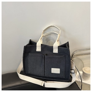 Détail du sac cabas minimaliste en toile grise avec doubles poches avant et sangles blanches