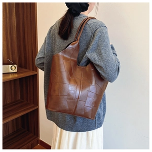Detail showing the geometric stitching and rich leather texture on a dark brown tote bag