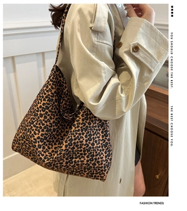 Detailweergave van een grote tote bag met luipaardprint gedragen bij een stijlvolle trenchcoat