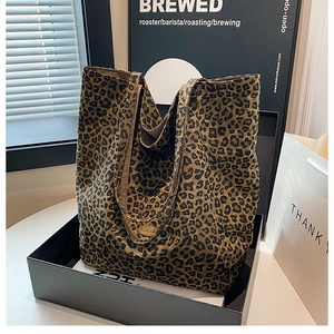 Close-up of handmade metal plaque on a leopard print canvas tote bag with wide strap