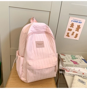 Detail of light pink backpack with textured vertical pleats and large front pocket