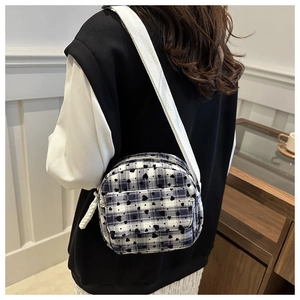 Close-up of blue and white checkered canvas shoulder bag with heart pattern and strap