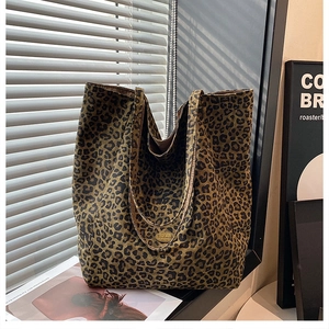 Detail of large leopard print tote bag with handmade metal emblem and wide canvas handles