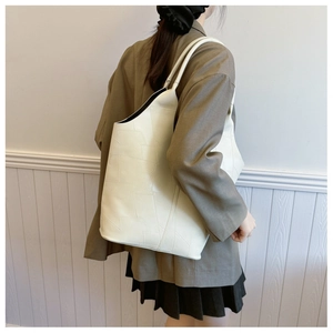 Detail of a large cream tote bag with geometric stitching and pebbled leather texture