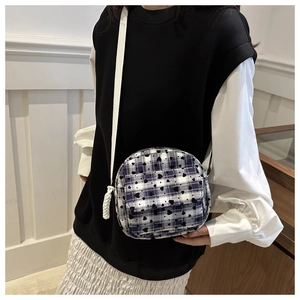 Detailed macro view of mini canvas crossbody bag with blue plaid and black heart patterns