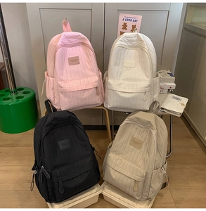 Detailed view of four minimalist nylon backpacks in pink, white, black, and beige colors