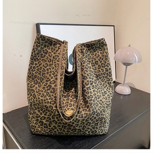 Close-up of leopard print canvas tote bag featuring an elegant gold metal logo charm