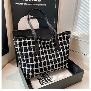 Dettaglio di una grande borsa tote in tweed a scacchi bianco e nero con manici in pelle