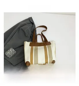 Vue détaillée du sac cabas en toile rayée avec détails renforcés en cuir brun