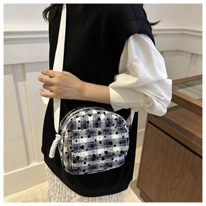 Detail of checkered canvas crossbody bag with heart prints and woven shoulder strap
