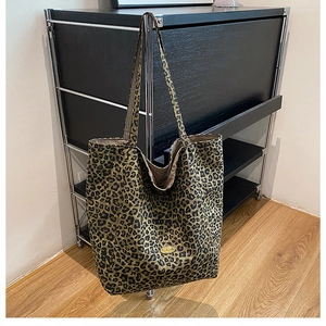 Close-up of leopard print tote bag featuring handmade gold logo plate and dual straps