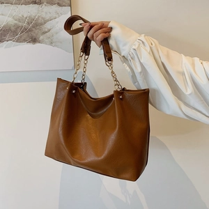 Sac cabas marron en similicuir avec chaîne dorée présenté dans un décor quotidien