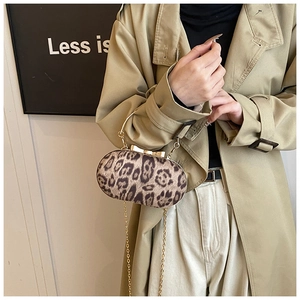 Gedetailleerde close-up van de luipaardclutch met gouden metalen handvat en striksluiting