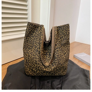 Detail of leopard print canvas tote bag with metal snap button on a wooden surface