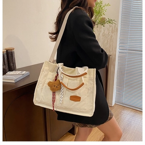 Close-up of cream corduroy tote bag featuring leather logo and stylish scarf decoration