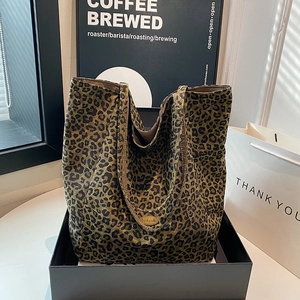 Detail of leopard print tote bag featuring a metallic handmade tag and brown lining
