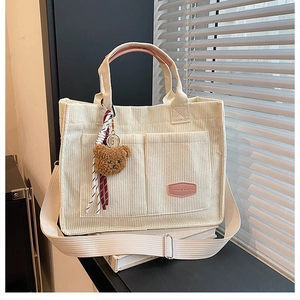 Detail of off-white corduroy tote bag with texture pockets and cute bear charm