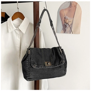 Detail of vintage black denim shoulder bag with retro bronze twist lock and chain strap