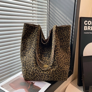 Detailed view of leopard print tote bag with handmade metal tag on canvas texture