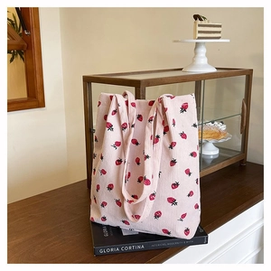 Dettaglio del tessuto a coste con motivi a fragola sulla borsa tote rosa in velluto