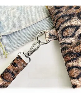 Close-up of leopard print bag with detachable silver metal hook on denim background