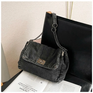 Close-up of retro charcoal denim shoulder bag with bronze twist-lock and chain strap