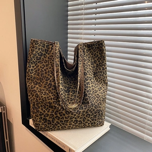 Detail of leopard print canvas tote bag featuring a vintage handmade metal logo plate