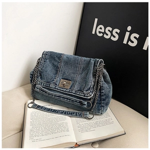 Detail of blue washed denim shoulder bag with silver turn-lock and chain strap