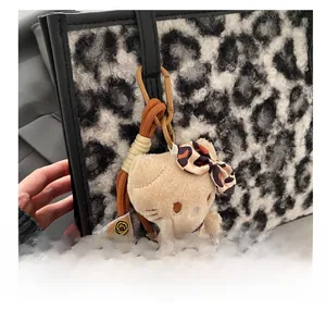 Détail d'un pendentif peluche chat avec nœud léopard sur un grand sac fourre-tout