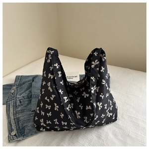 Detailopname van zwarte canvas shopper met witte strikjes op een wit laken