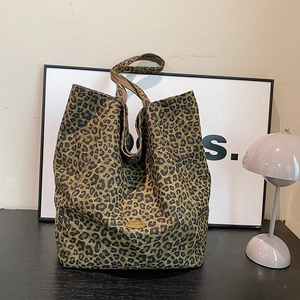Close-up of leopard print tote bag fabric with handmade golden metal logo tag detail